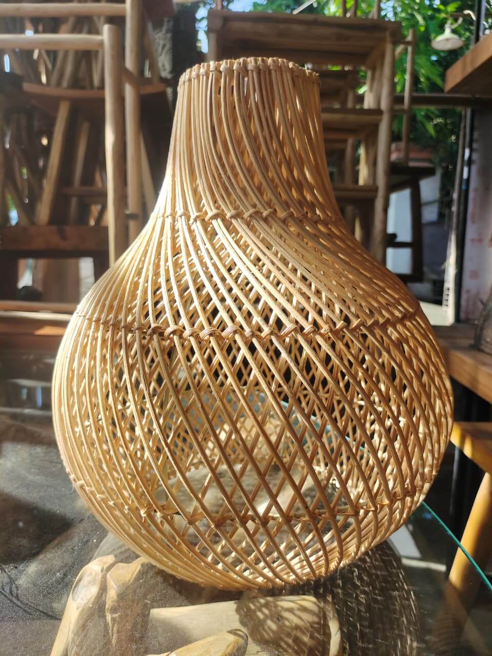 Lampshade rotan handmade dengan siluet bulat dan leher ramping serta anyaman vertikal diagonal