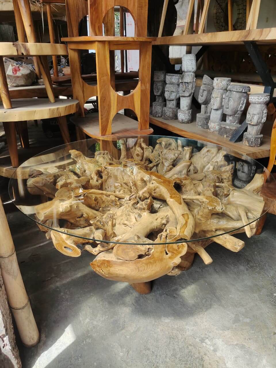 Meja tamu dari akar kayu alami yang eksotis dengan top kaca bulat transparan di atasnya.