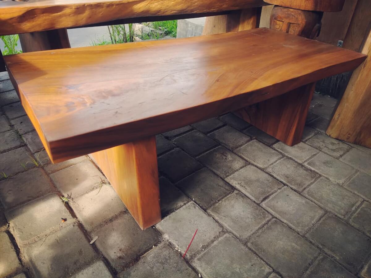 Meja tamu kayu solid masif dengan permukaan lebar dan kaki kayu yang tebal.