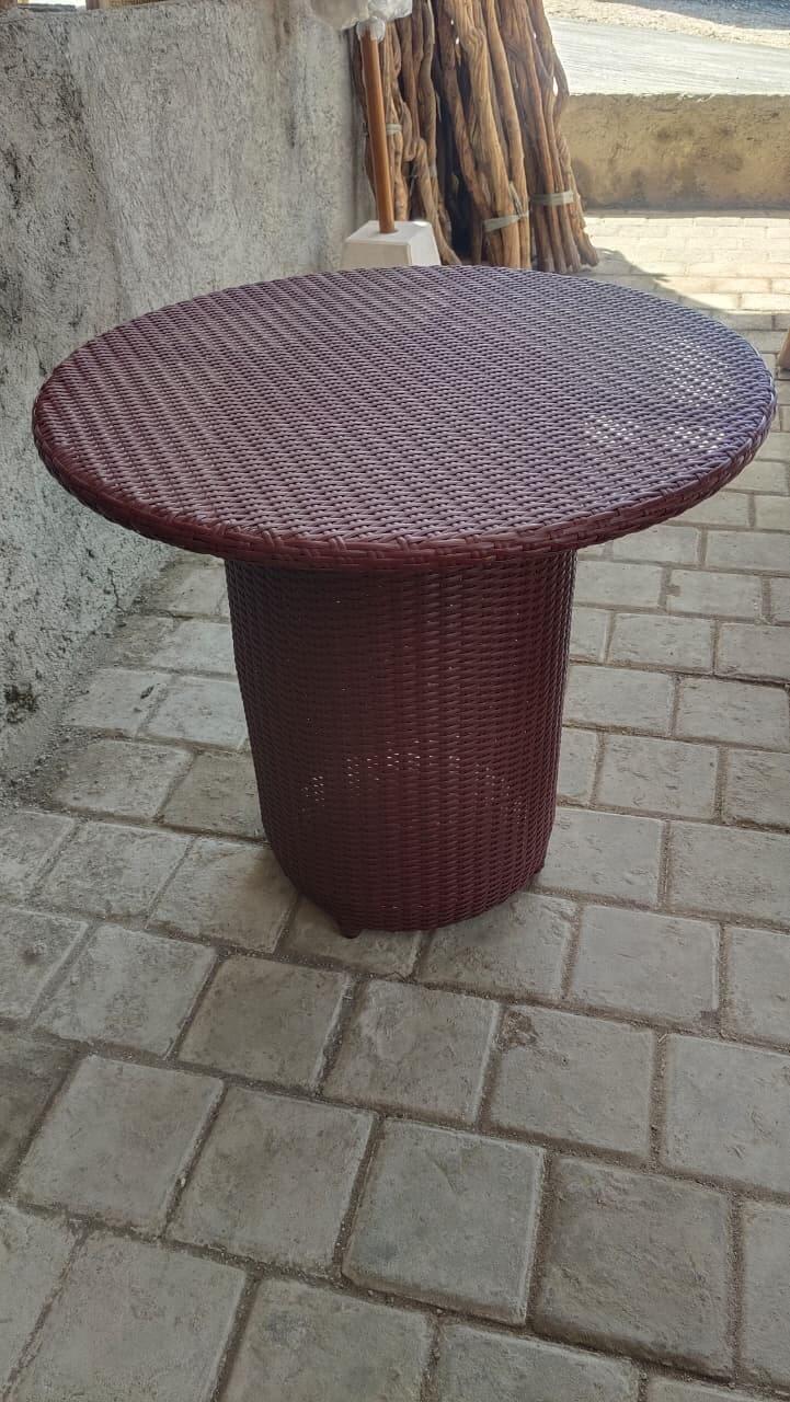 Meja rotan sintetis bundar warna maroon dengan anyaman rapat